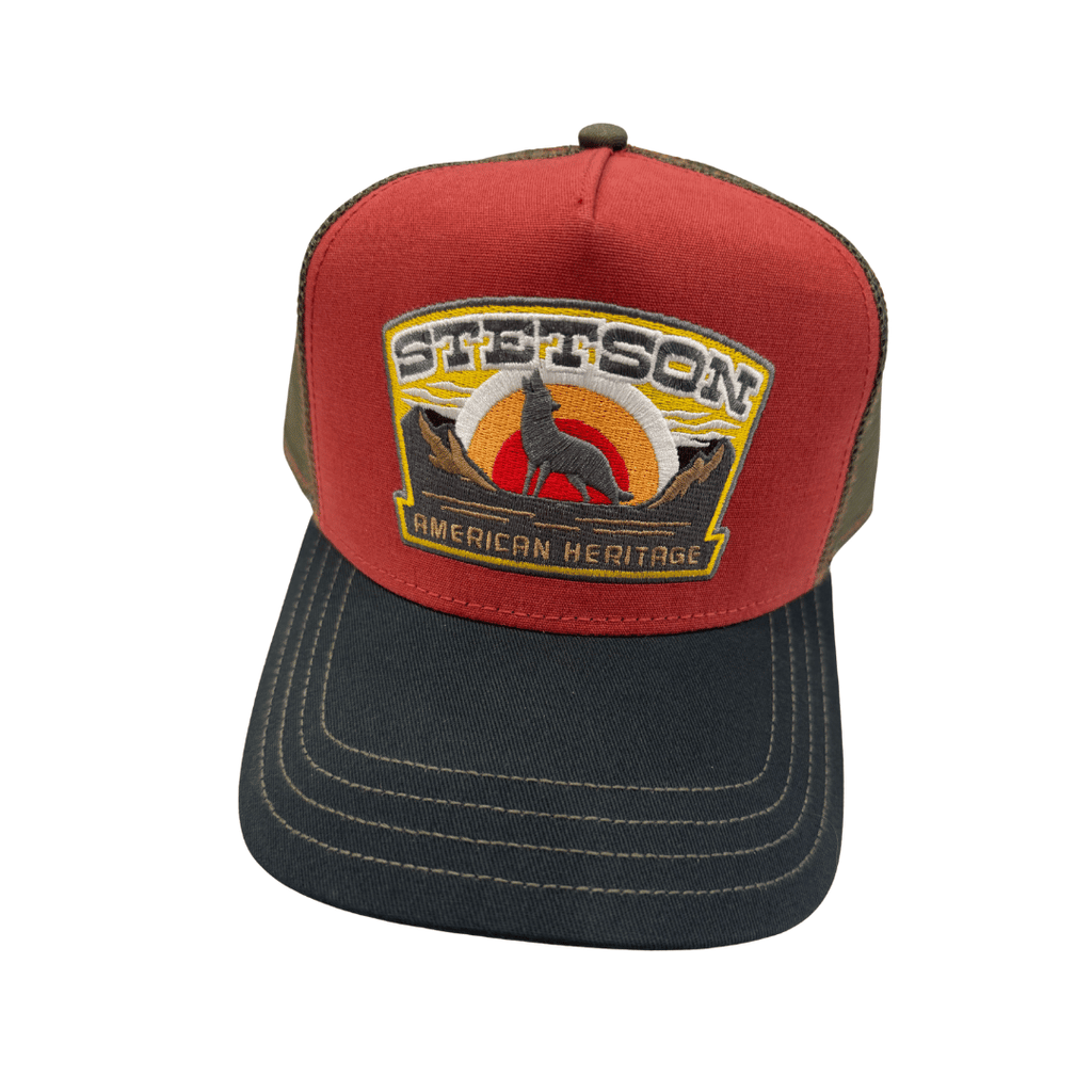 A red and dark gray trucker hat with a Stetson American Heritage patch on the front, set against a plain white background. Official Stetson Stockist Isabella Josie Sussex Hats