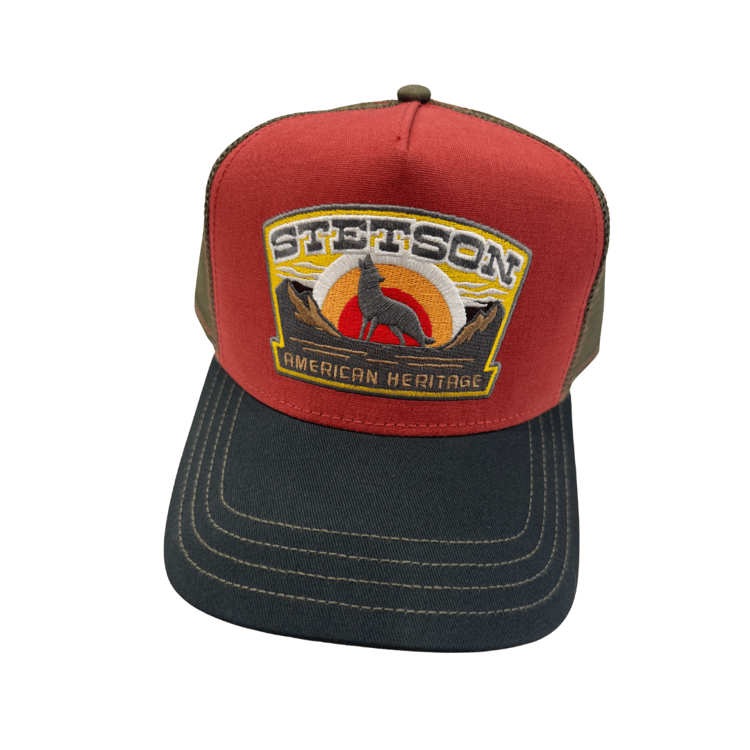 A red and dark gray trucker hat with a Stetson American Heritage patch on the front, set against a plain white background. Official Stetson Stockist Isabella Josie Sussex Hats